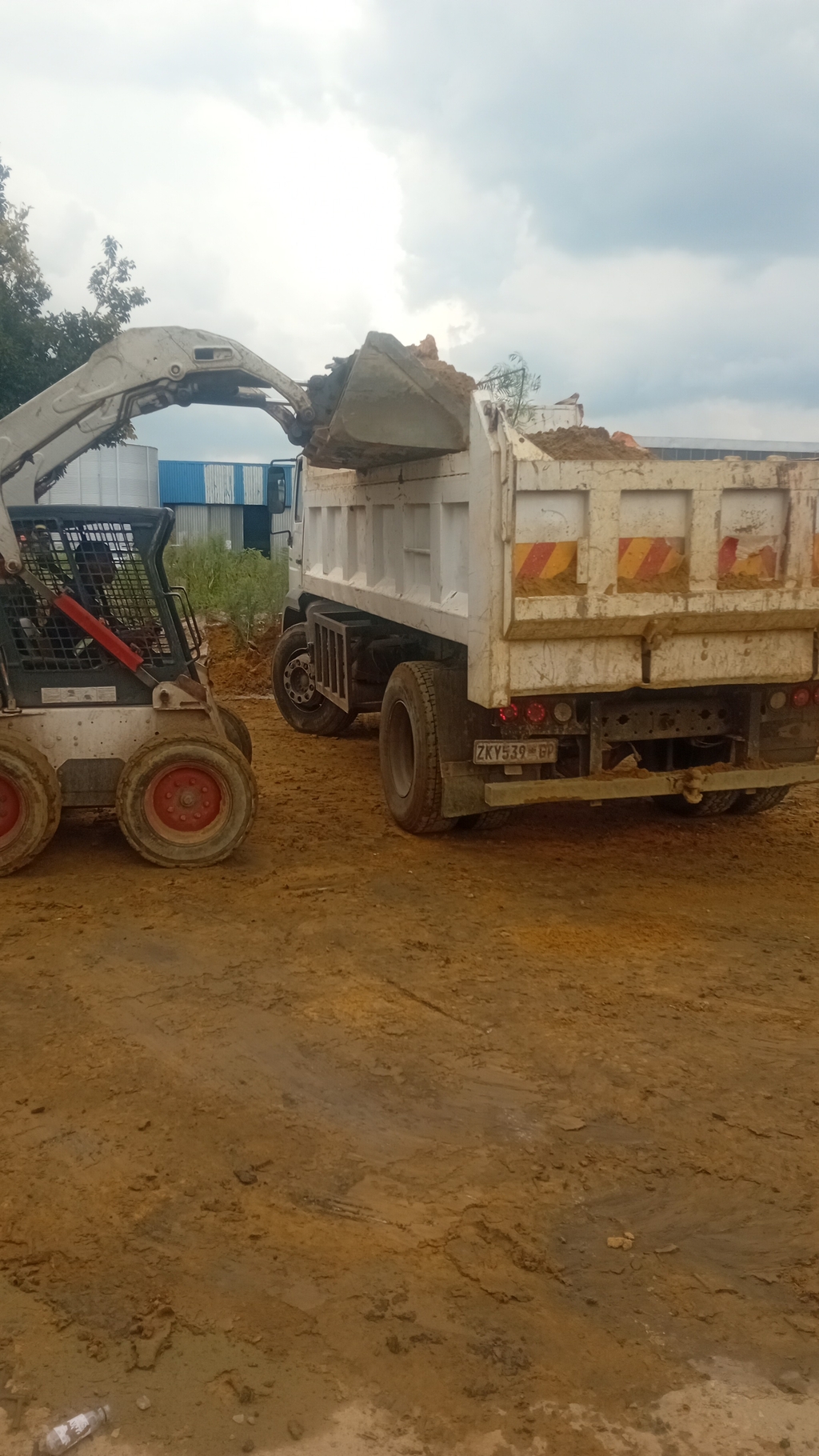 A Bob cat and truck loading  building rubbles